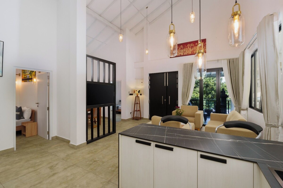Interior moderno com ilha na cozinha, área de refeições e vista para o exterior.