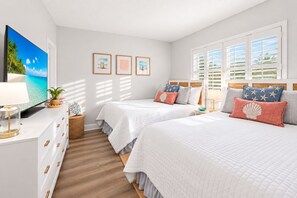 A hotel room with two beds, a TV, a dresser, and a window with shutters. - Dunes Dream Just 100 Steps from the Beach (Jensen Beach)