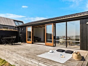 A wooden deck with a covered seating area, a barbecue grill, and a large sliding glass door leading to an indoor space. - 4 Person Holiday Home in Ronde (Ronde)