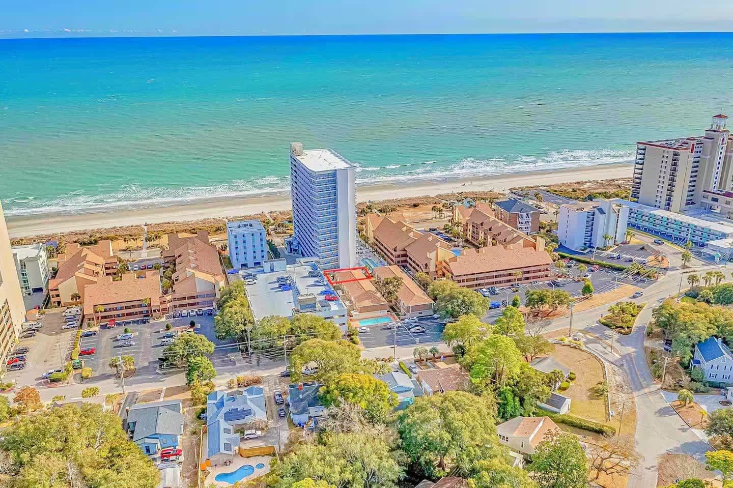A coastal town with a mix of residential and commercial buildings, a beach, and a clear view of the ocean.