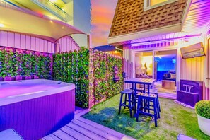 Ein Whirlpool, eine Holzterrasse und eine Sitzgelegenheit im Freien mit Blick ins Innere des Gebäudes.