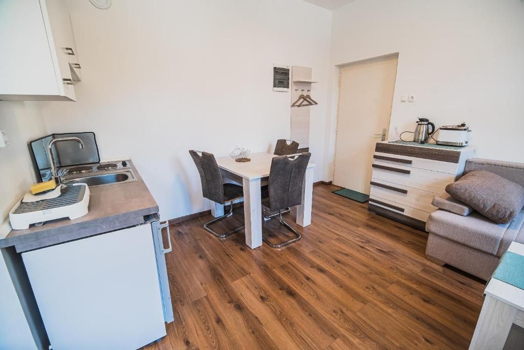 A compact kitchen with a dining table and chairs, a small refrigerator, and a coffee maker on the counter.