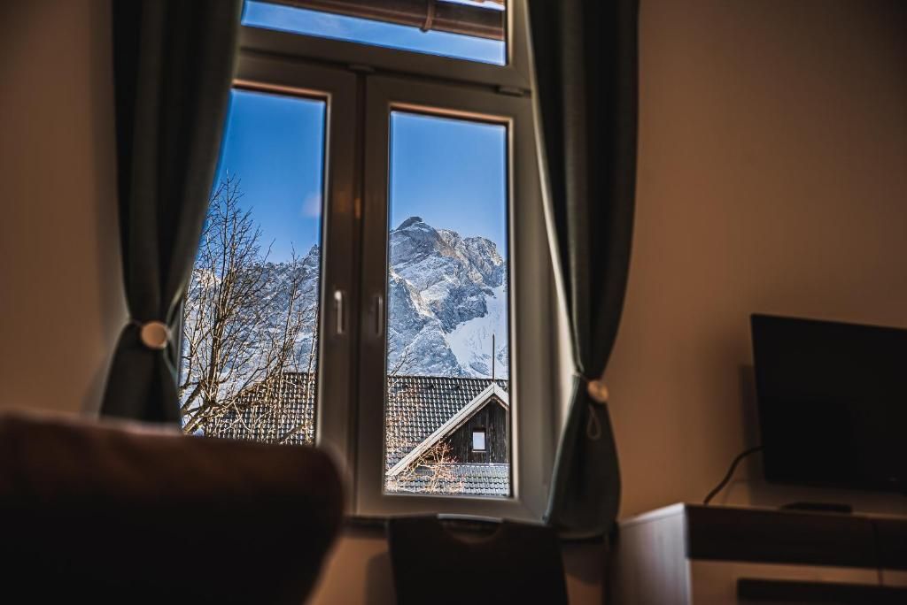 Una ventana con vistas a un paisaje montañoso, un televisor y una silla.