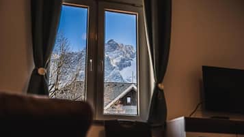 Una ventana con vistas a un paisaje montañoso, un televisor y una silla.