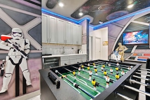 A room with a foosball table, Star Wars decorations, and a ceiling with a space-themed mural. - Luxury 15BR Suites, Pool and Themed Bedrooms (Williamsburg)
