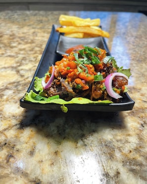 A dish with meat, vegetables, and a side of fries on a plate.