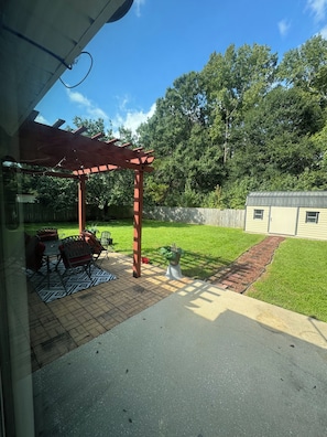 Ein überdachter Patio-Bereich mit einer Pergola, Gartenmöbeln und einem kleinen Garten.