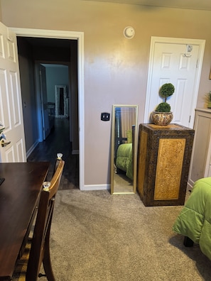 Une pièce comprenant une table à manger, un miroir, une petite plante en pot et une porte donnant sur une autre pièce.
