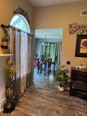 A dining area with a chandelier, a table with chairs, and a window with curtains. - Cozy Family Home away from Home
3-bedroom house in beautiful Pooler w/everything (Pooler)