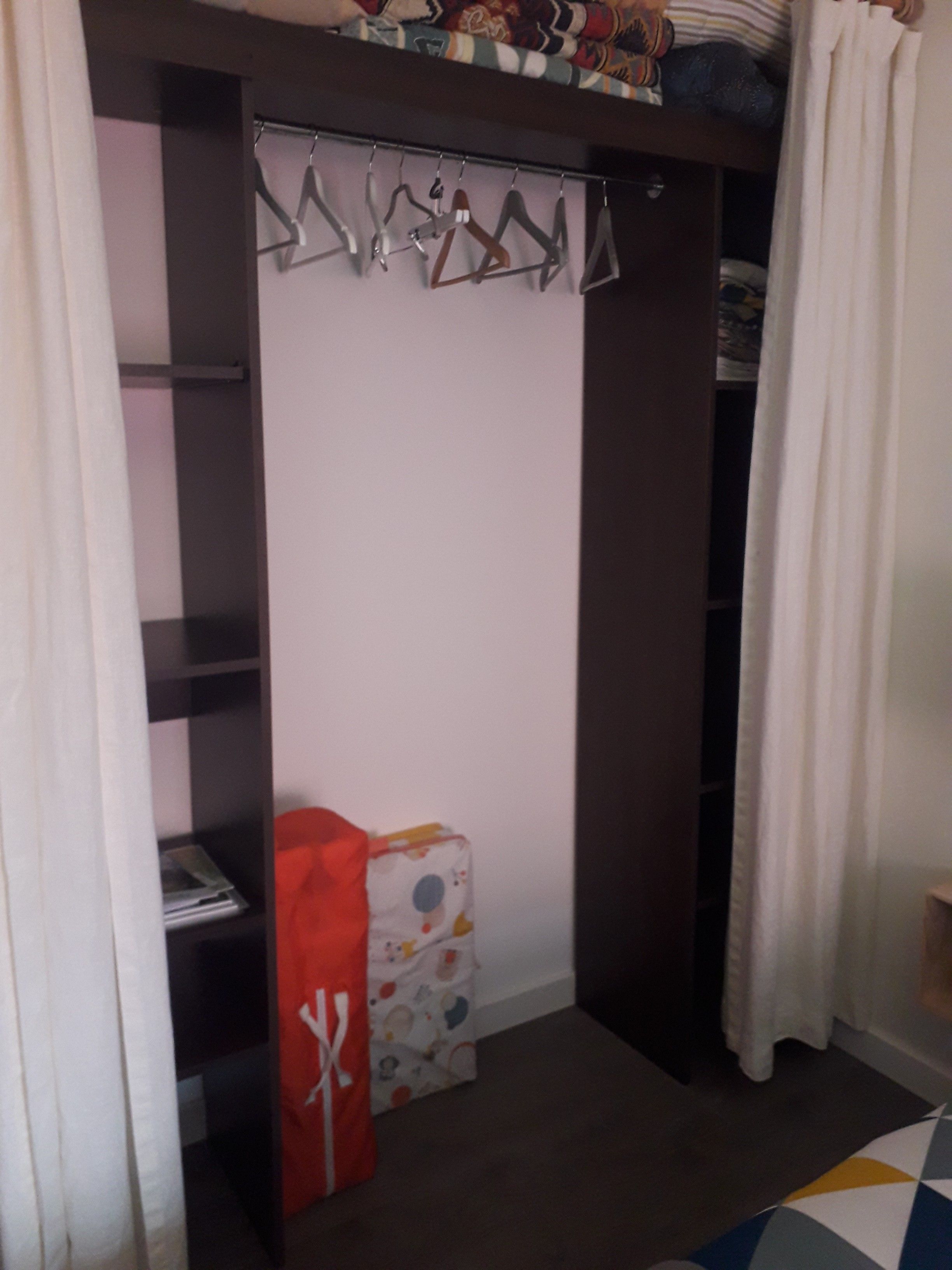 A closet with a hanging rod, a shelf, and a folded item on the floor.