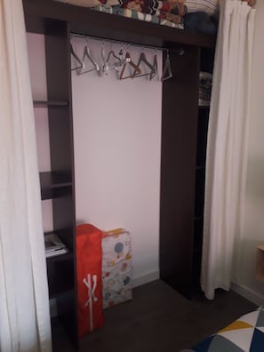 A closet with a hanging rod, a shelf, and a folded item on the floor.