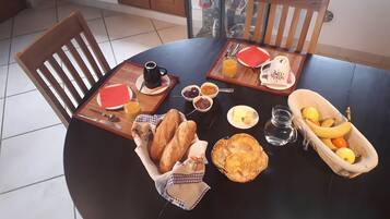 A round dining table set with breakfast items including bread, pancakes, fruit, and condiments.