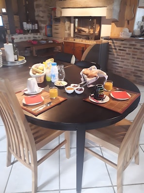 Ein Frühstückstisch ist reichhaltig gedeckt, mit verschiedenen Speisen, einer Kaffeemaschine und einer Gitarre im Hintergrund.