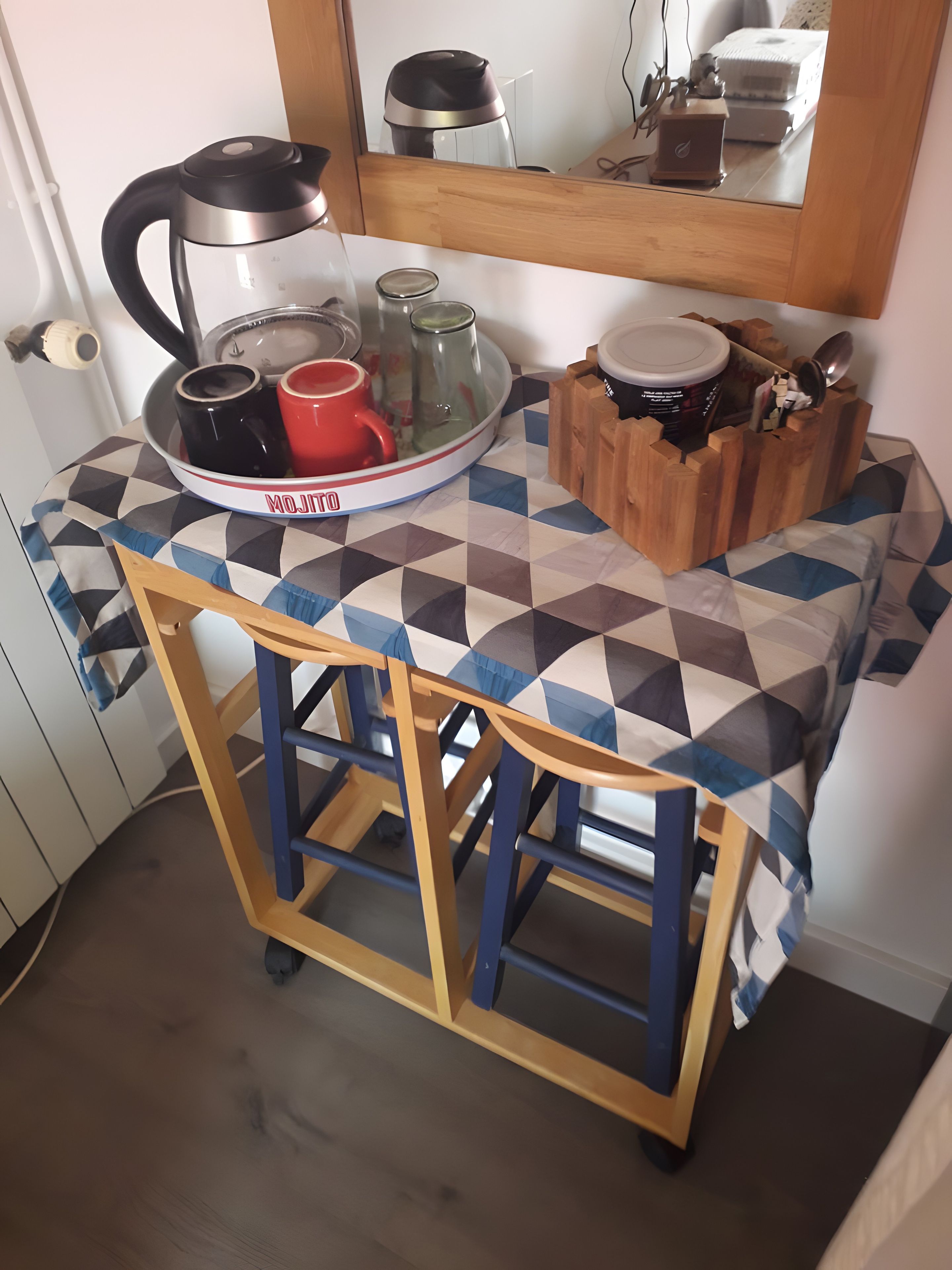 Ein kleiner Küchenbereich mit Tisch, Stuhl und einer Tablett mit Geschirr.