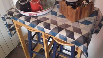 Ein kleiner Küchenbereich mit Tisch, Stuhl und einer Tablett mit Geschirr.