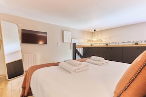 Een hotelkamer met een bed, een televisie, een bureau met een lamp en een trap.