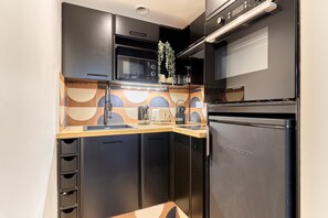 A compact kitchen with a microwave, toaster, and refrigerator. - Apartment Le Marais/ Place des Vosges (Paris)