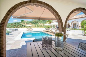 A poolside area with a clear view of a swimming pool, lounge chairs, and a table with glasses and a pitcher. - Apartment for two among olive groves in Andalusia (Alcaucin)