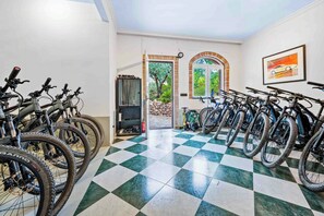 A bicycle rental area with multiple bikes, a checkered floor, and a view of greenery through an open door. - Apartment for two among olive groves in Andalusia (Alcaucin)