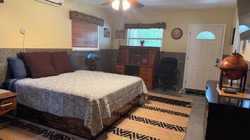 A bedroom with a bed, a desk, a globe, and a window with blinds.