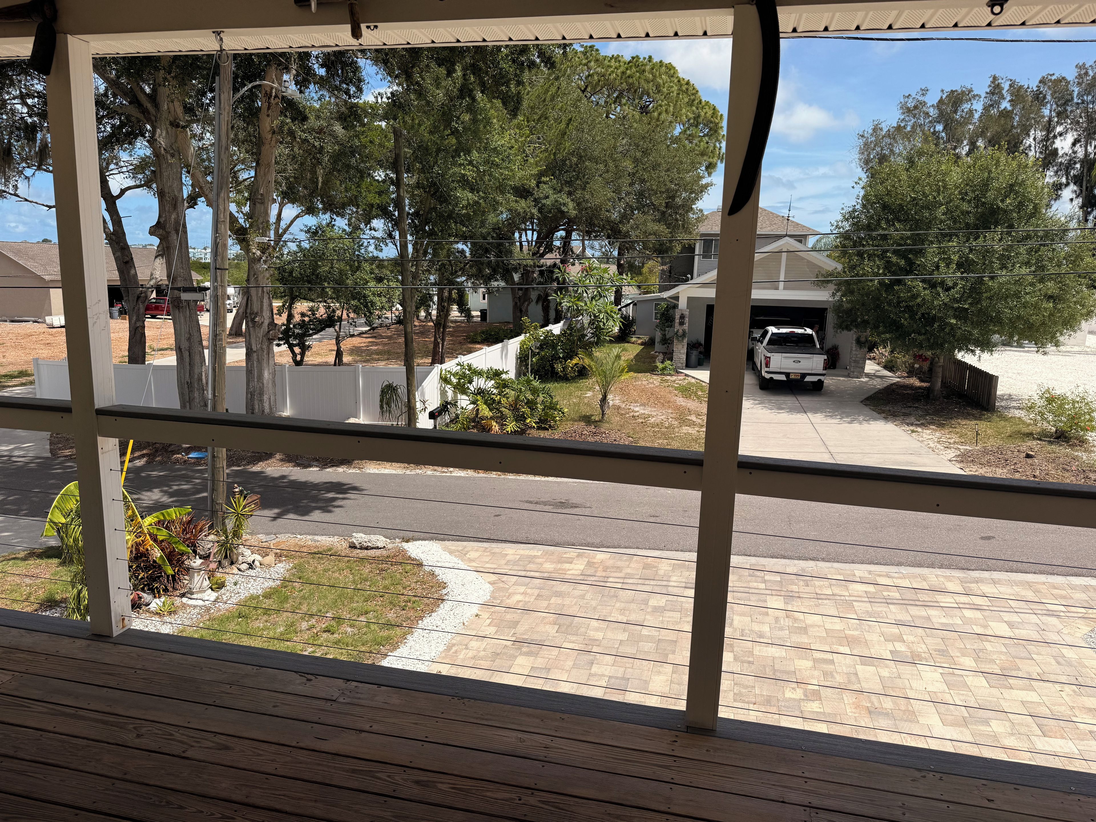A residential street view from a porch with a view of houses, a driveway, and a parked vehicle.