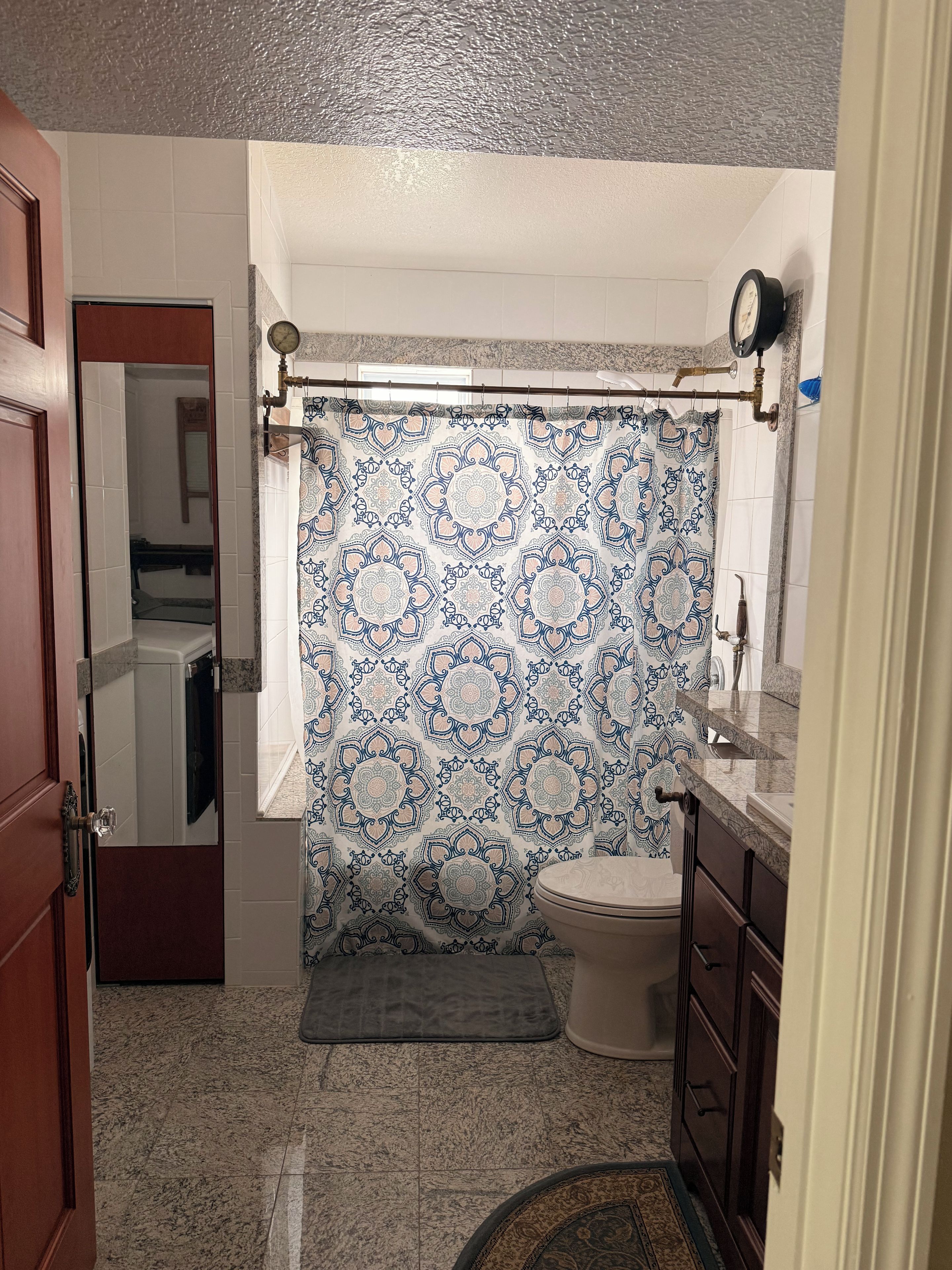 Un baño con cortina de ducha estampada, un inodoro, un lavabo y un espejo.