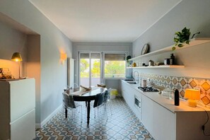 A compact kitchen with a dining table, chairs, a refrigerator, a sink, and a window with a view of greenery. - Casa degli ASPRI - apartment in the center of Vasto (Vasto)