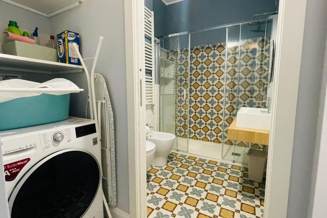 Ein kleines Badezimmer mit Waschmaschine, Toilette und Duschkabine.