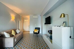 A living room with a sofa, a chair, a television, a refrigerator, and a patterned floor. - Casa degli ASPRI - apartment in the center of Vasto (Vasto)
