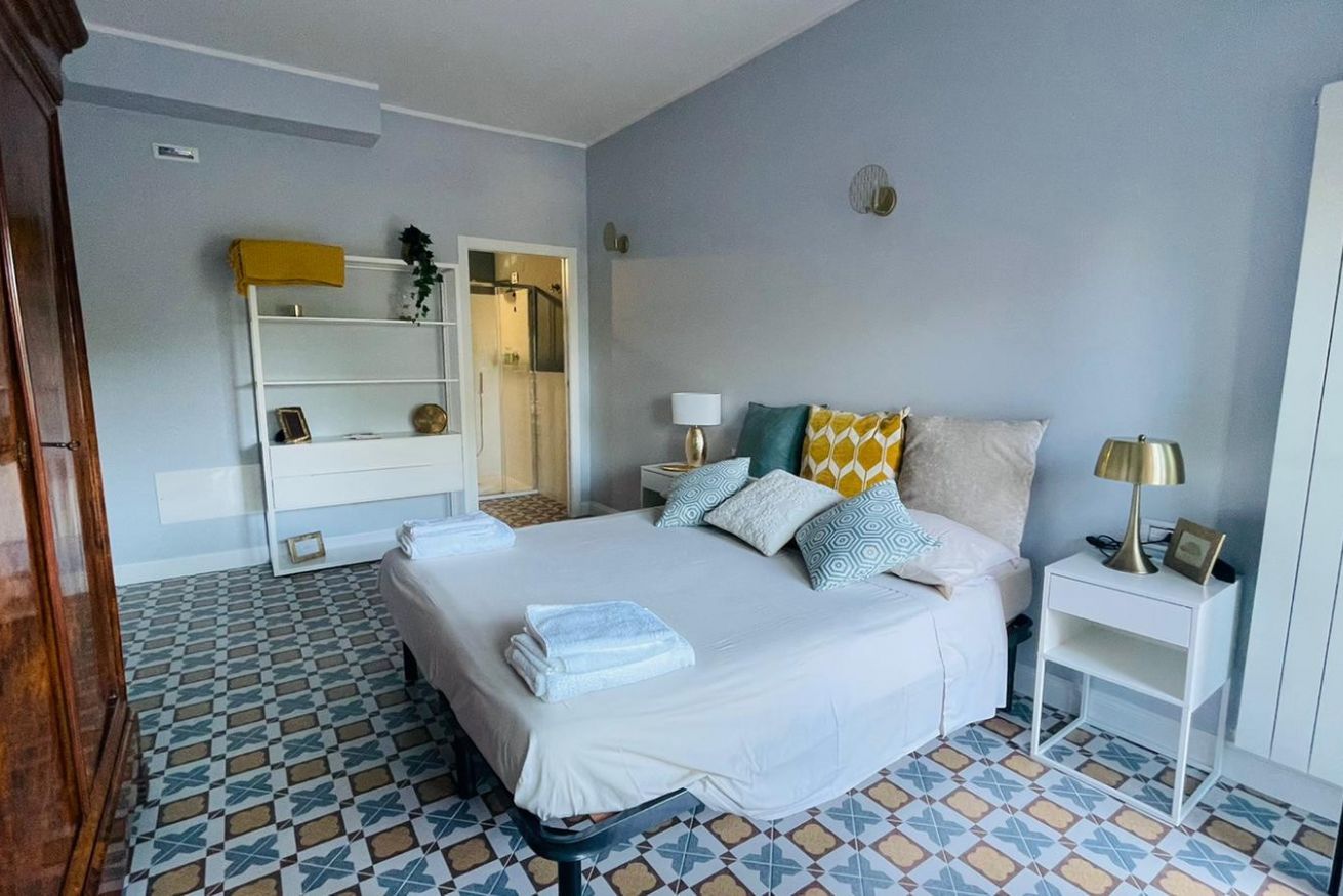Habitación de hotel con cama, mesitas de noche, armario y baño visible a través de una puerta abierta.