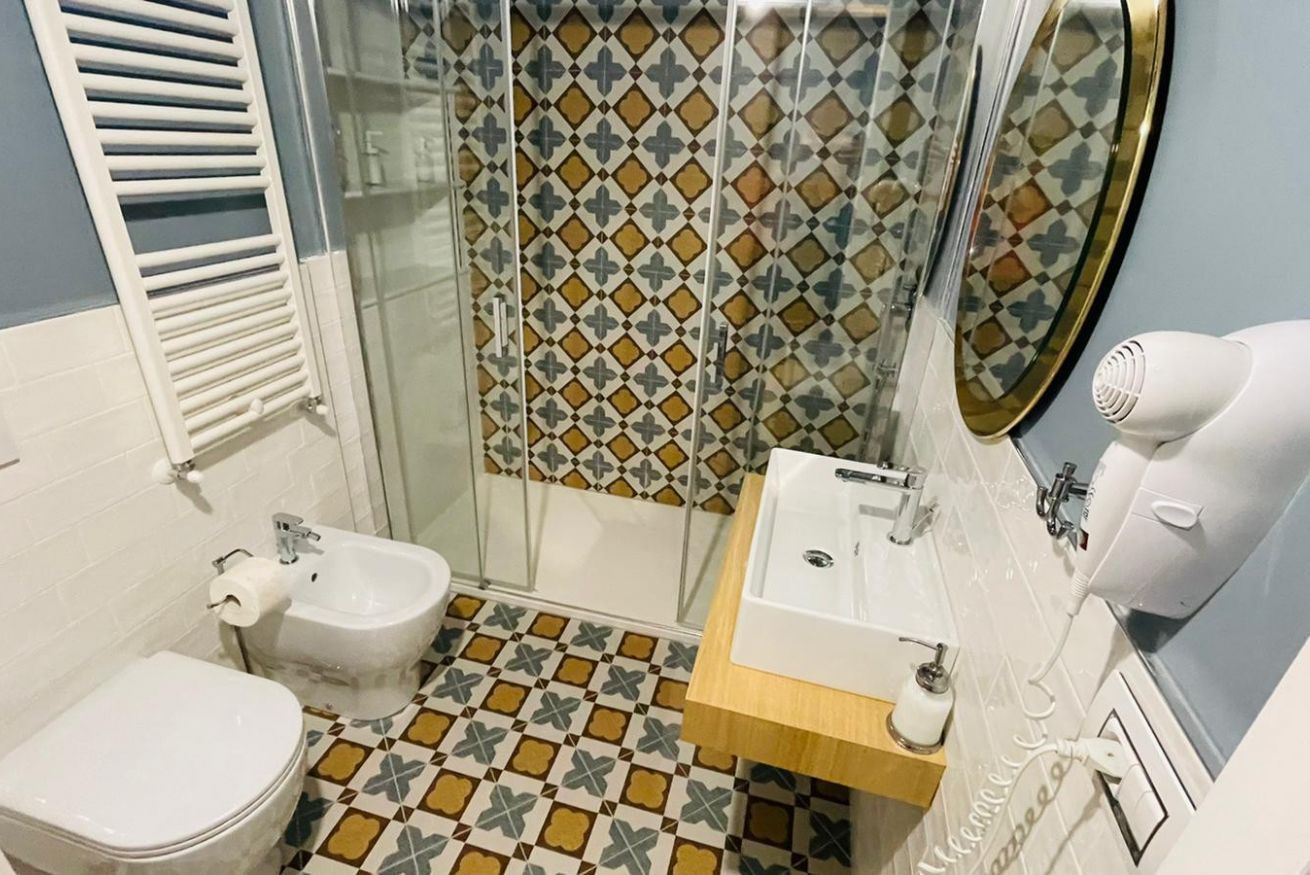A bathroom with a toilet, bidet, shower enclosure, sink, and a hairdryer.
