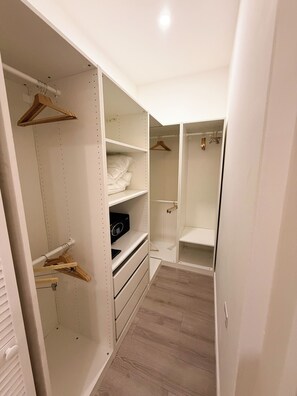 A walk-in closet with open shelves, hanging space, and a wooden floor. - Walk to Beach Modern 1-Bed Apt CasaAmarilla205 (Oranjestad)