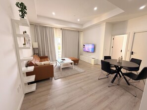 A modern living room with a sofa, coffee table, and dining area. - Walk to Beach Modern 1-Bed Apt CasaAmarilla205 (Oranjestad)
