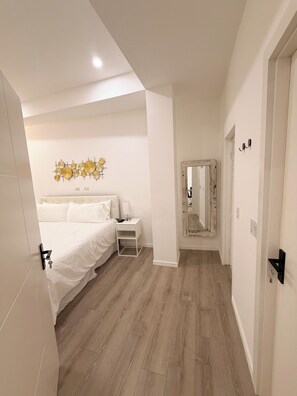 A bedroom with a bed, bedside table, and a wall-mounted decorative piece. - Walk to Beach Modern 1-Bed Apt CasaAmarilla205 (Oranjestad)
