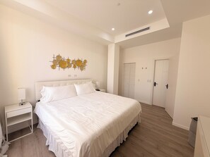 A bedroom with a bed, bedside table, wall art, and a wardrobe. - Walk to Beach Modern 1-Bed Apt CasaAmarilla205 (Oranjestad)