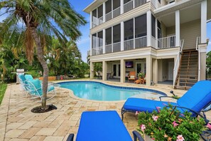 A two-story house with a swimming pool, outdoor seating, and a balcony. - Pet-Friendly Canal Retreat  Pool & Balconies (Bonita Springs)