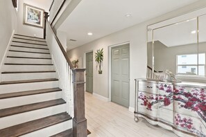 A staircase with wooden steps and a handrail, leading to a room with a large mirror and a floral-patterned dresser. - Pet-Friendly Canal Retreat  Pool & Balconies (Bonita Springs)