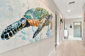 Un passadís amb un mural gran d'una tortuga marina, una porta i un carret.