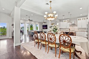 A spacious dining area with a large round table, wooden chairs, and a chandelier. - Pet-Friendly Canal Retreat  Pool & Balconies (Bonita Springs)