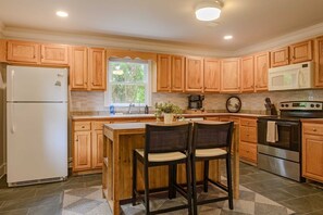 A kitchen with wooden cabinets, a refrigerator, a coffee maker, and a stove. - Ridgeview Home with Hot Tub in Lookout Valley (Chattanooga)