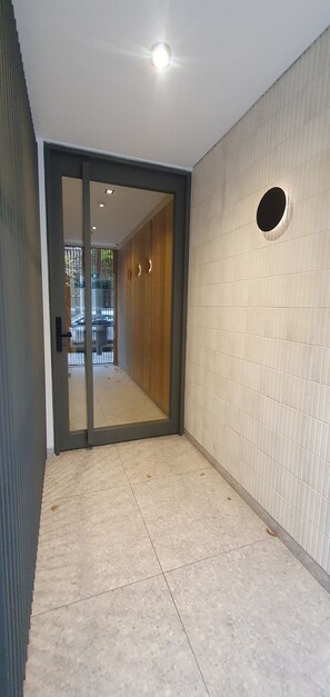 A corridor with a tiled floor, a door leading to a hallway, and a wall with a circular cut-out. - Bright Apartment in Palermo Soho (Buenos Aires)