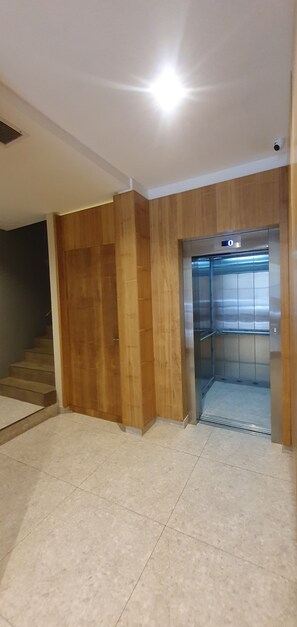 A hallway with a wooden wall and a tiled floor leading to an elevator. - Bright apartment in Palermo Soho (Buenos Aires)