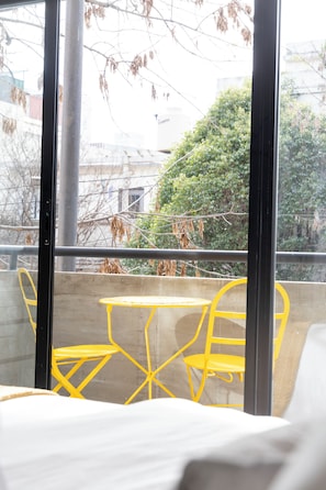 A balcony with yellow chairs and a table, overlooking a building and trees. - Bright Apartment in Palermo Soho (Buenos Aires)