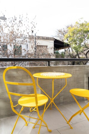 A yellow metal chair and table set on a balcony with a view of buildings and trees. - Bright apartment in Palermo Soho (Buenos Aires)