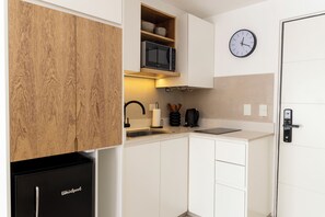 A compact kitchen with white cabinetry, a built-in microwave, a sink, and a clock on the wall. - Bright apartment in Palermo Soho (Buenos Aires)