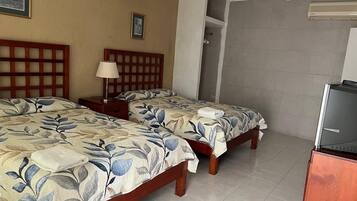 A hotel room with two beds, a nightstand, a lamp, a shower area, and a minibar.