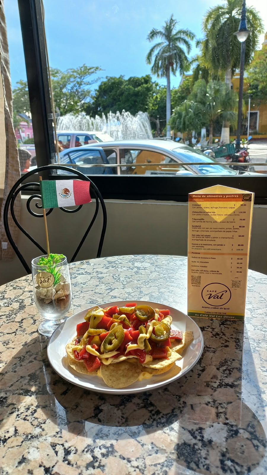 Una mesa de comedor con un plato de comida, un menú y una pequeña bandera.