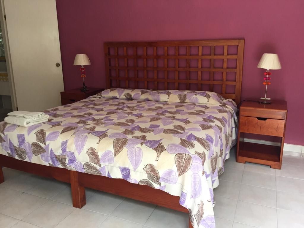 A bedroom with a wooden bed, two bedside tables, and a nightstand.