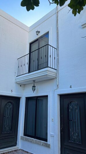 A building with a white facade, a balcony with a black railing, and two black doors with decorative glass panels.