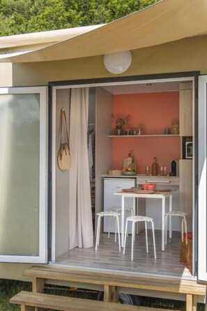 Un espacio habitable compacto con kitchenette, zona de comedor y puerta corrediza que da a un balcón.